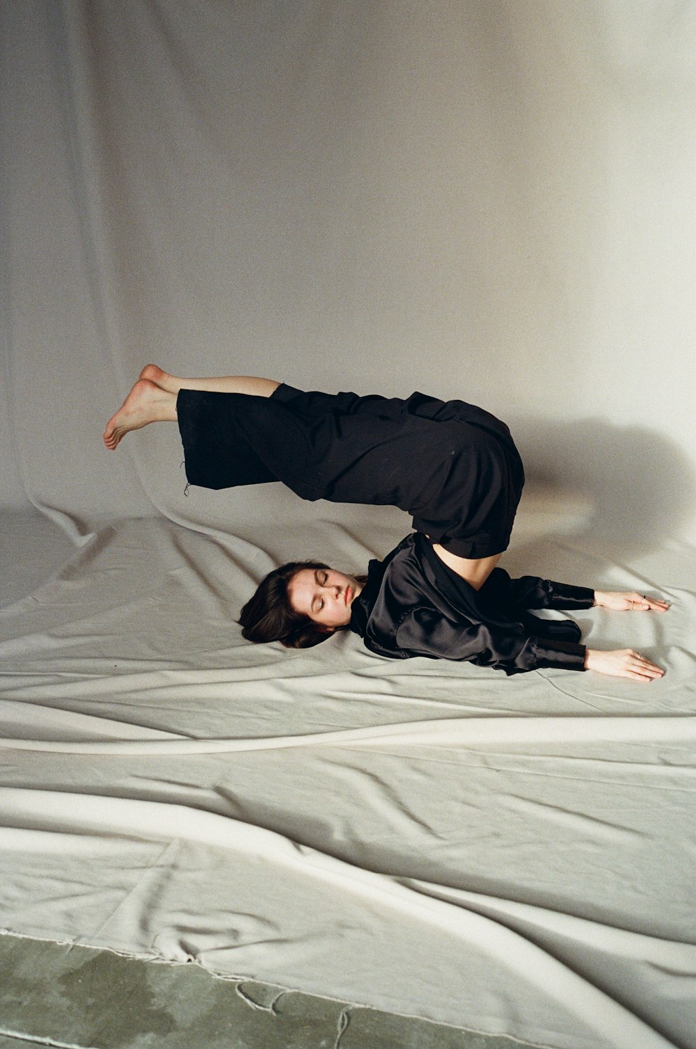 a woman laying on top of a bed on top of a white sheet