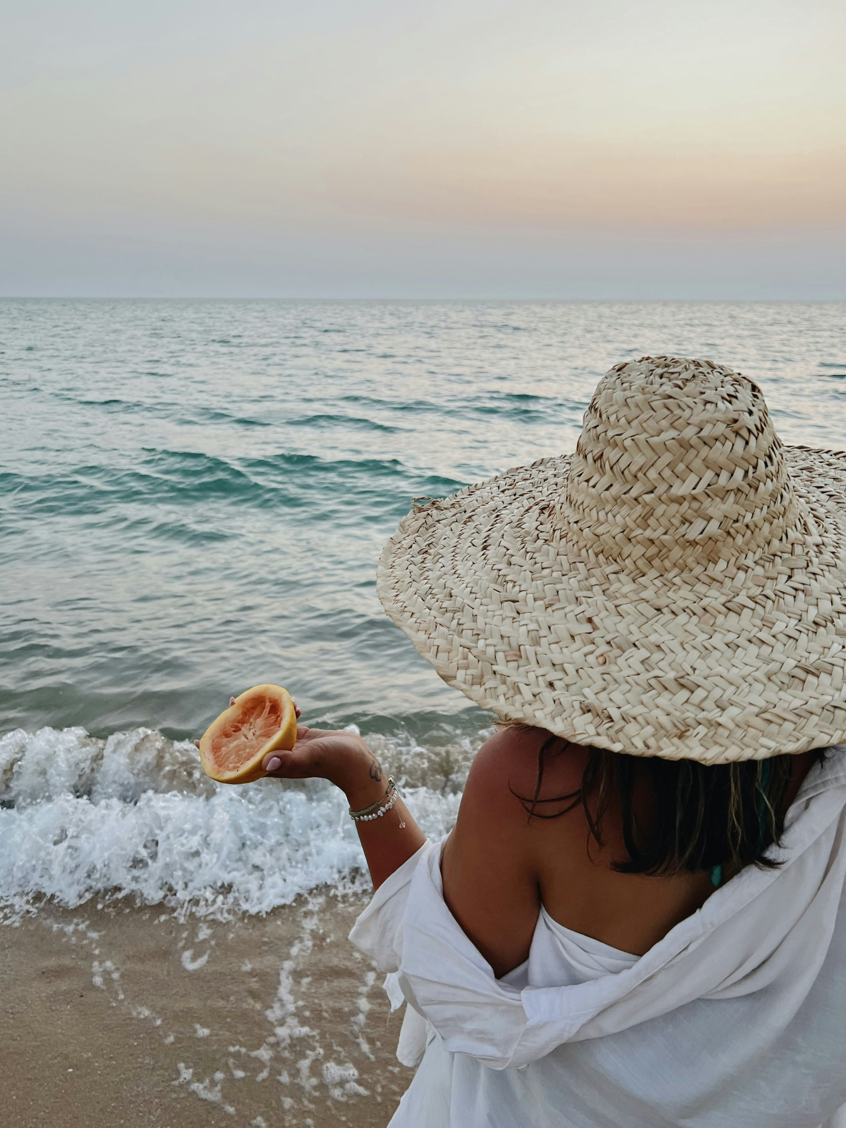 a woman in a straw hat is on the beach
