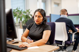 A professional customer service representative wearing a headset, ready to assist.