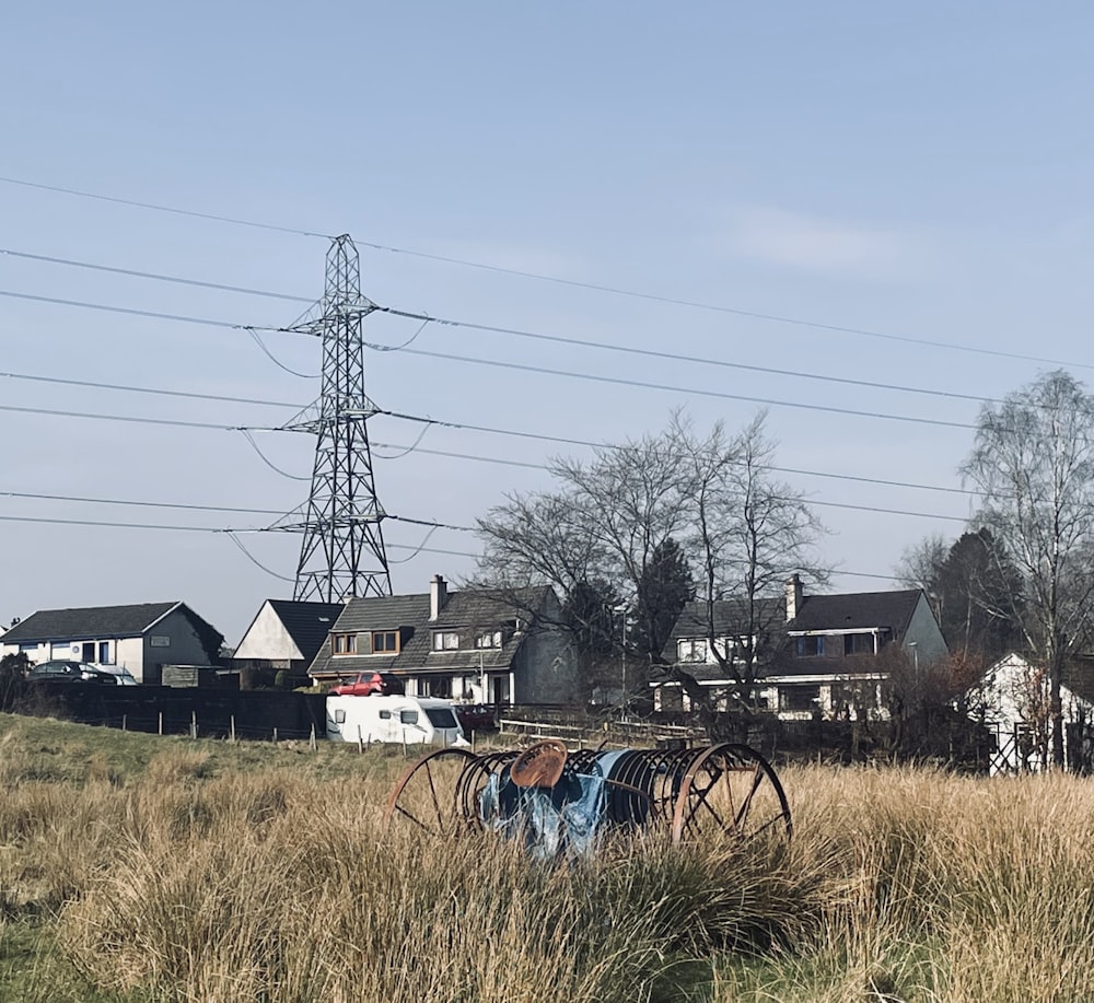 an old wagon in a field with houses in the background