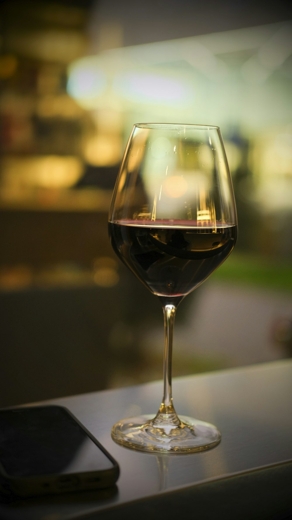 um copo de vinho e um telefone celular em uma mesa