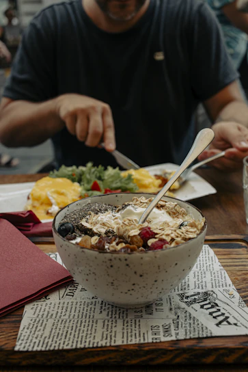 Cyclist preparing a nutritious meal before a long ride, with fresh fruits and energy bars on a wooden table.