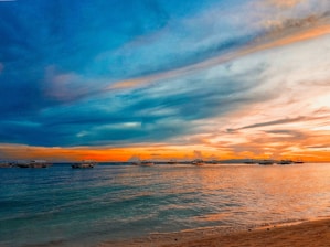 A vibrant sunset over the Kisite Mpunguti Marine Park with boats gently floating on calm waters.