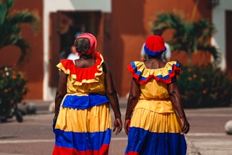 two women in colorful dresses walking down a street