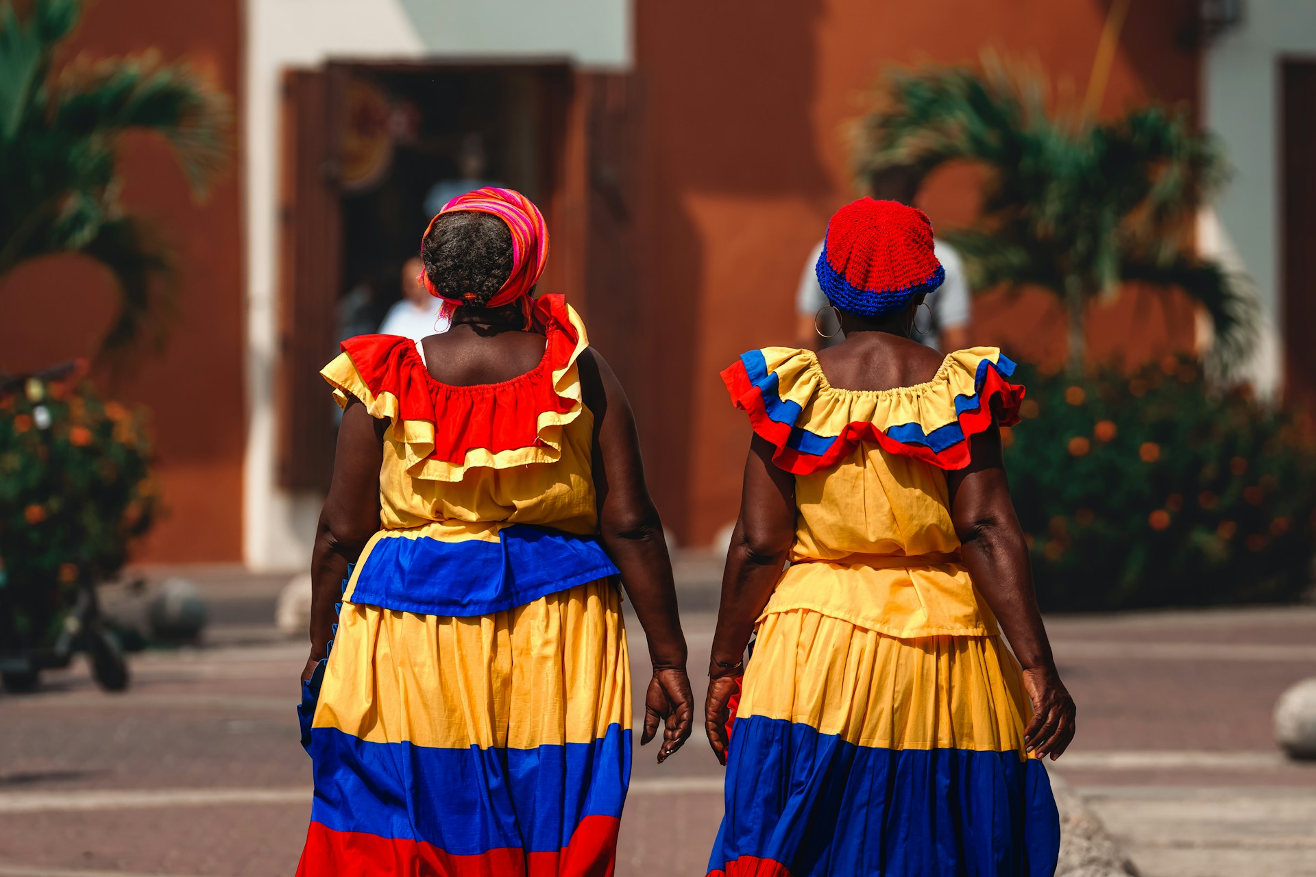 two women in colorful dresses walking down a street