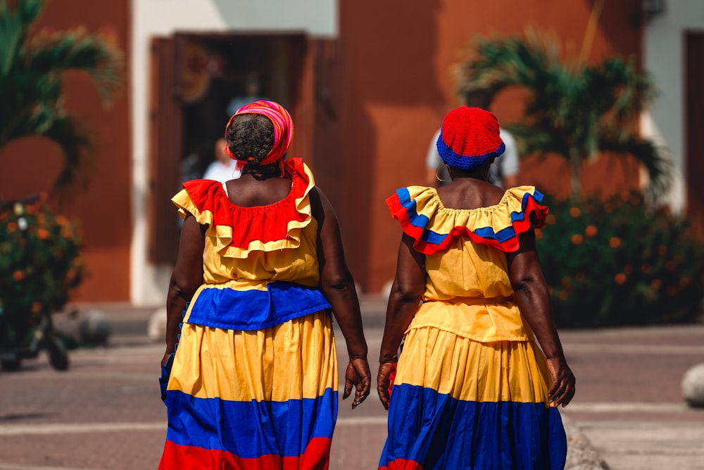 two women in colorful dresses walking down a street