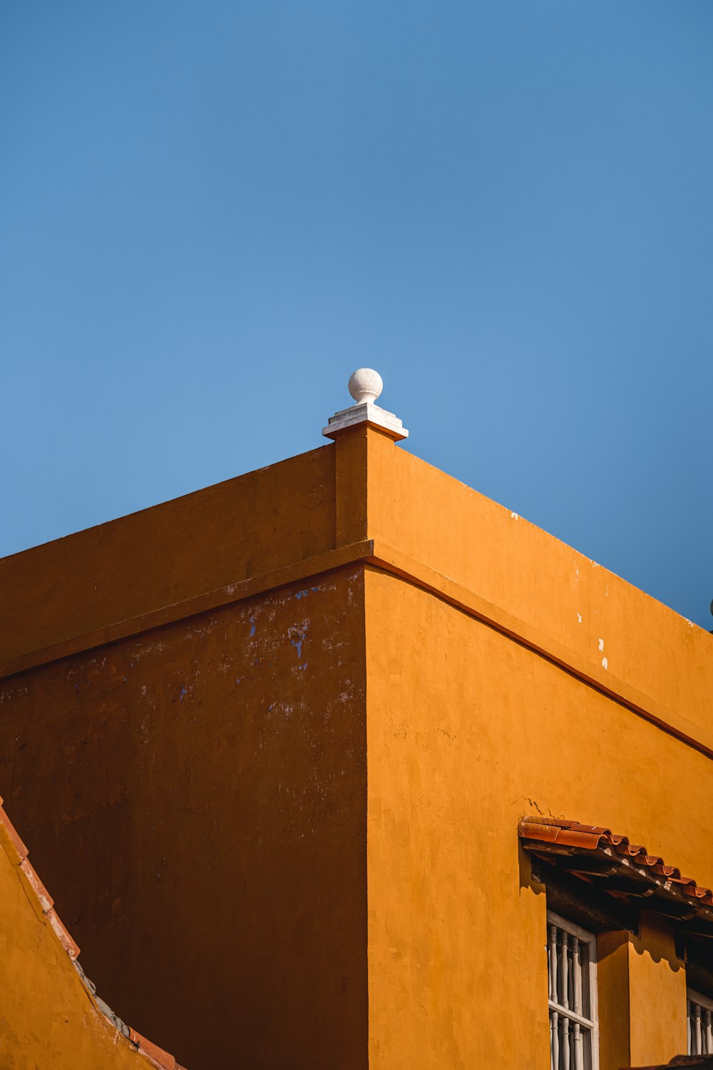 a yellow building with a white roof and a blue sky in the background