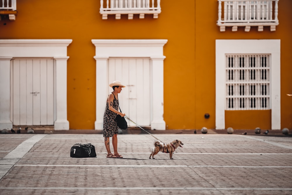 a woman with a suitcase and a dog on a leash