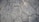 A textured surface composed of irregularly shaped stone tiles, each tile defined by distinct edges and a slightly weathered appearance. The stones vary in size and pattern, showing subtle variations in color and surface detail.