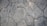 A textured surface composed of irregularly shaped stone tiles, each tile defined by distinct edges and a slightly weathered appearance. The stones vary in size and pattern, showing subtle variations in color and surface detail.