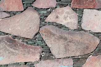 Large irregular stone slabs of various sizes are meticulously arranged with dark mortar visible in between, forming a rustic and textured pattern.