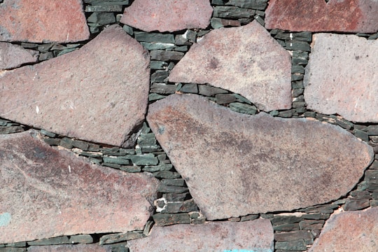 Large irregular stone slabs of various sizes are meticulously arranged with dark mortar visible in between, forming a rustic and textured pattern.