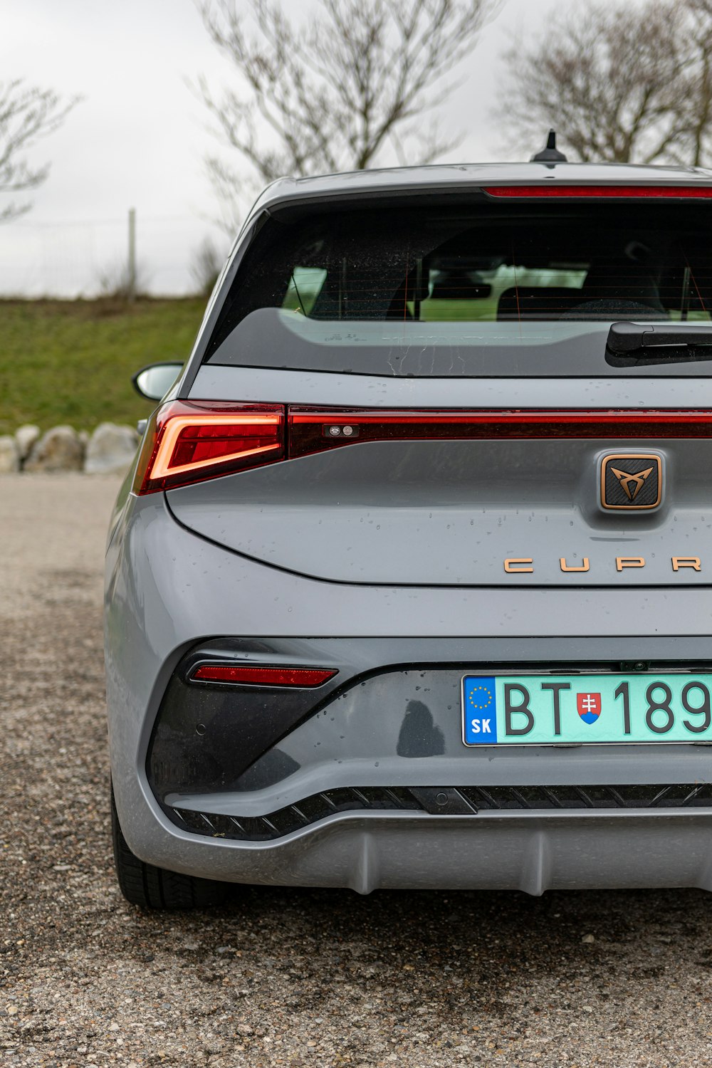 the rear end of a grey car with a license plate