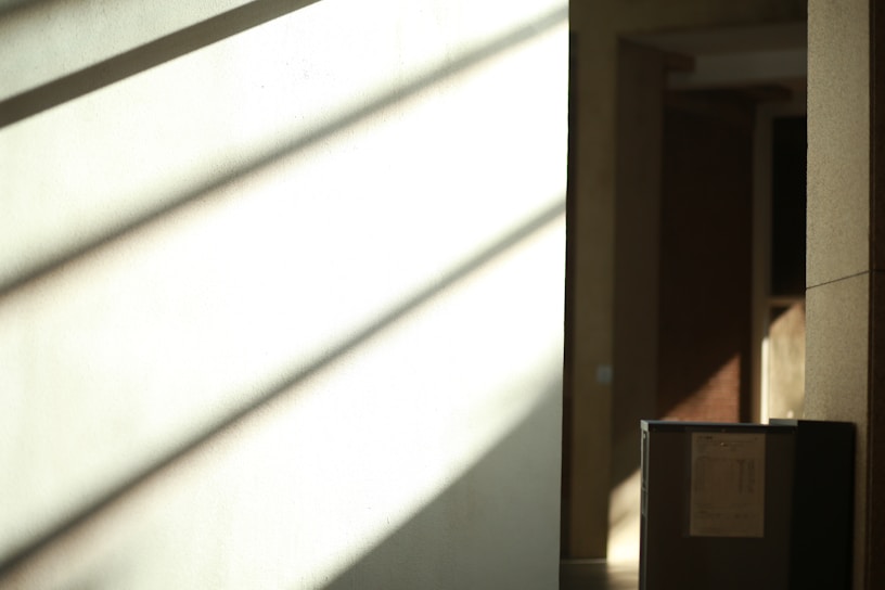 Vertical close-up of soft golden light casting shadows on an off-white textured wall.