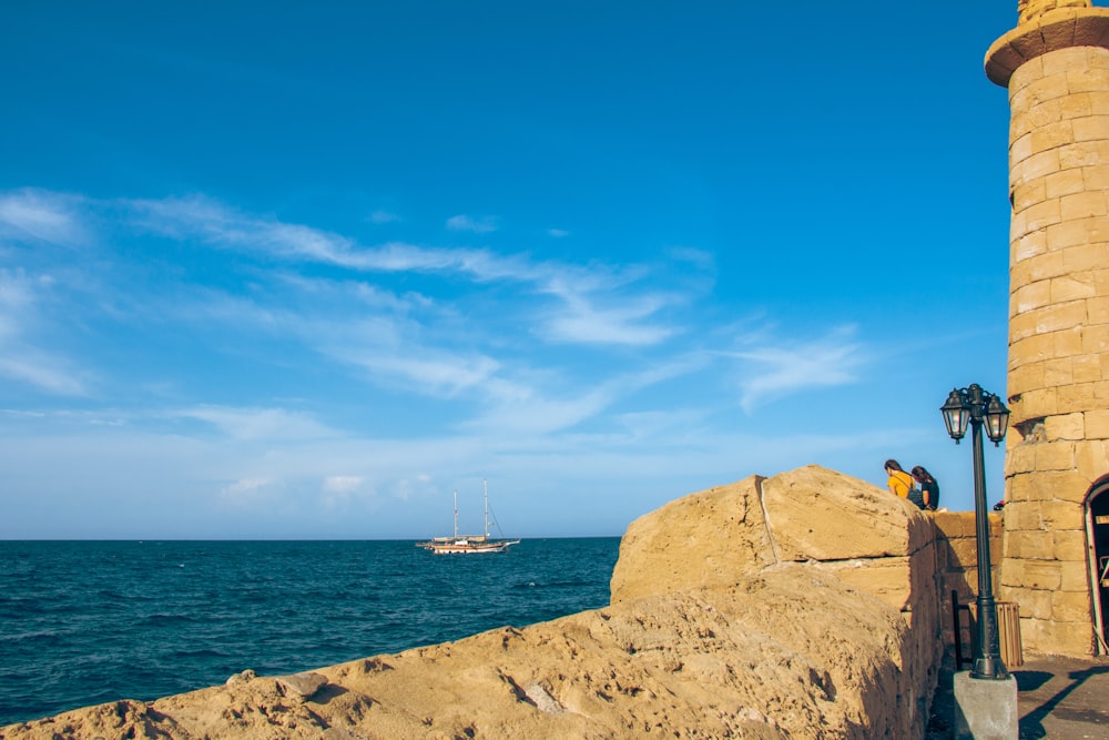 a lighthouse on a beach with a boat in the background