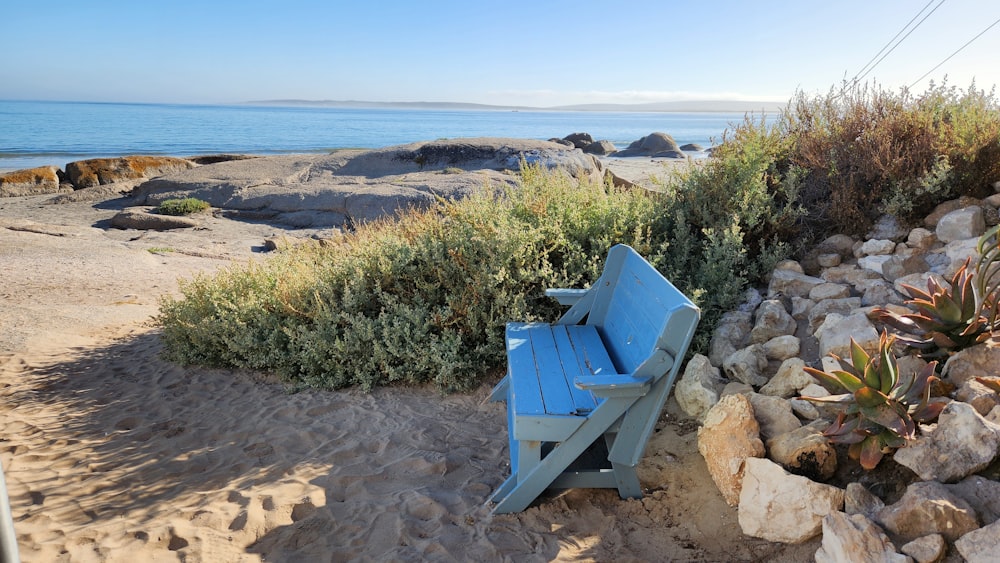 a blue bench sitting on top of a sandy beach