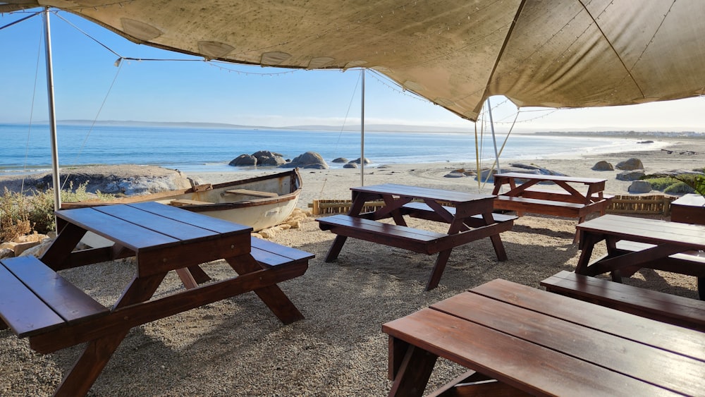picnic tables and benches under an umbrella on a beach