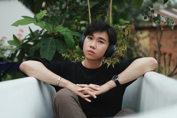 A serene outdoor scene with headphones resting on a wooden bench beside a notebook.