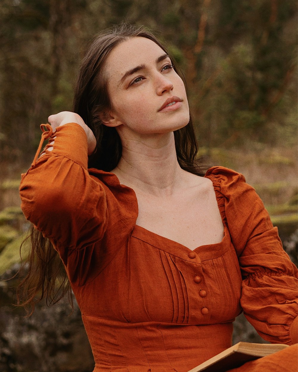 a woman in an orange dress sitting in a forest