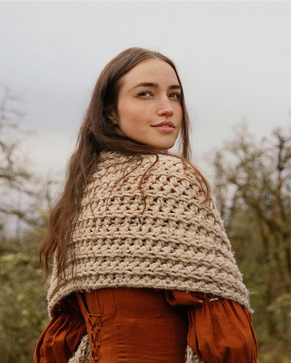a woman is wearing a crocheted shawl
