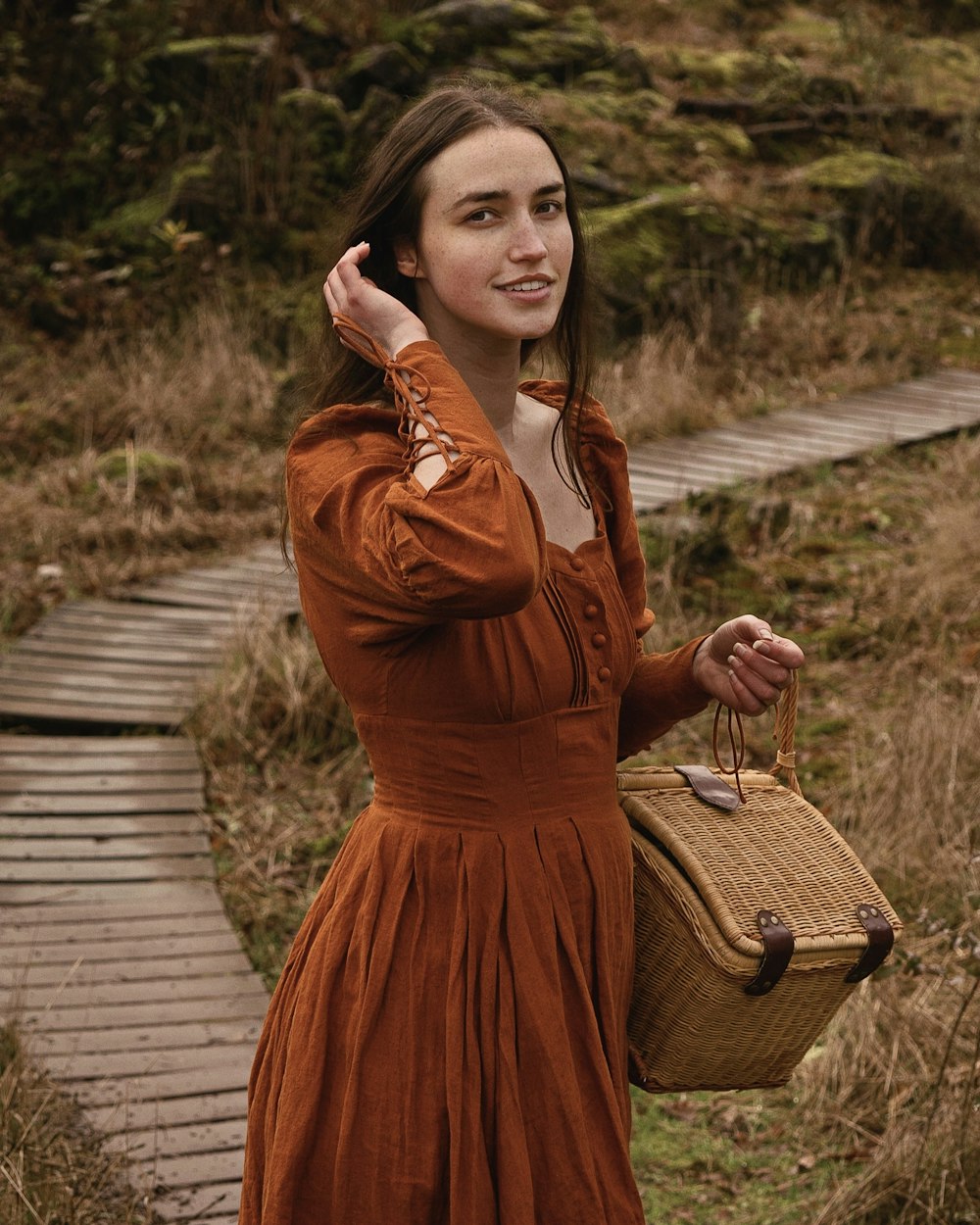 Eine Frau in einem orangefarbenen Kleid hält einen Korb in der Hand