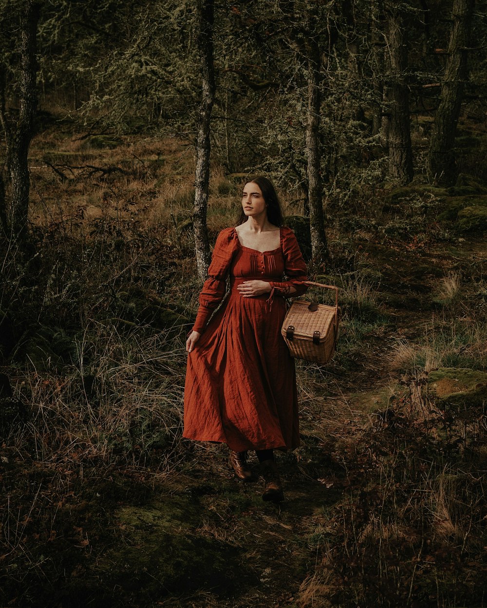 a woman in a red dress is walking through the woods