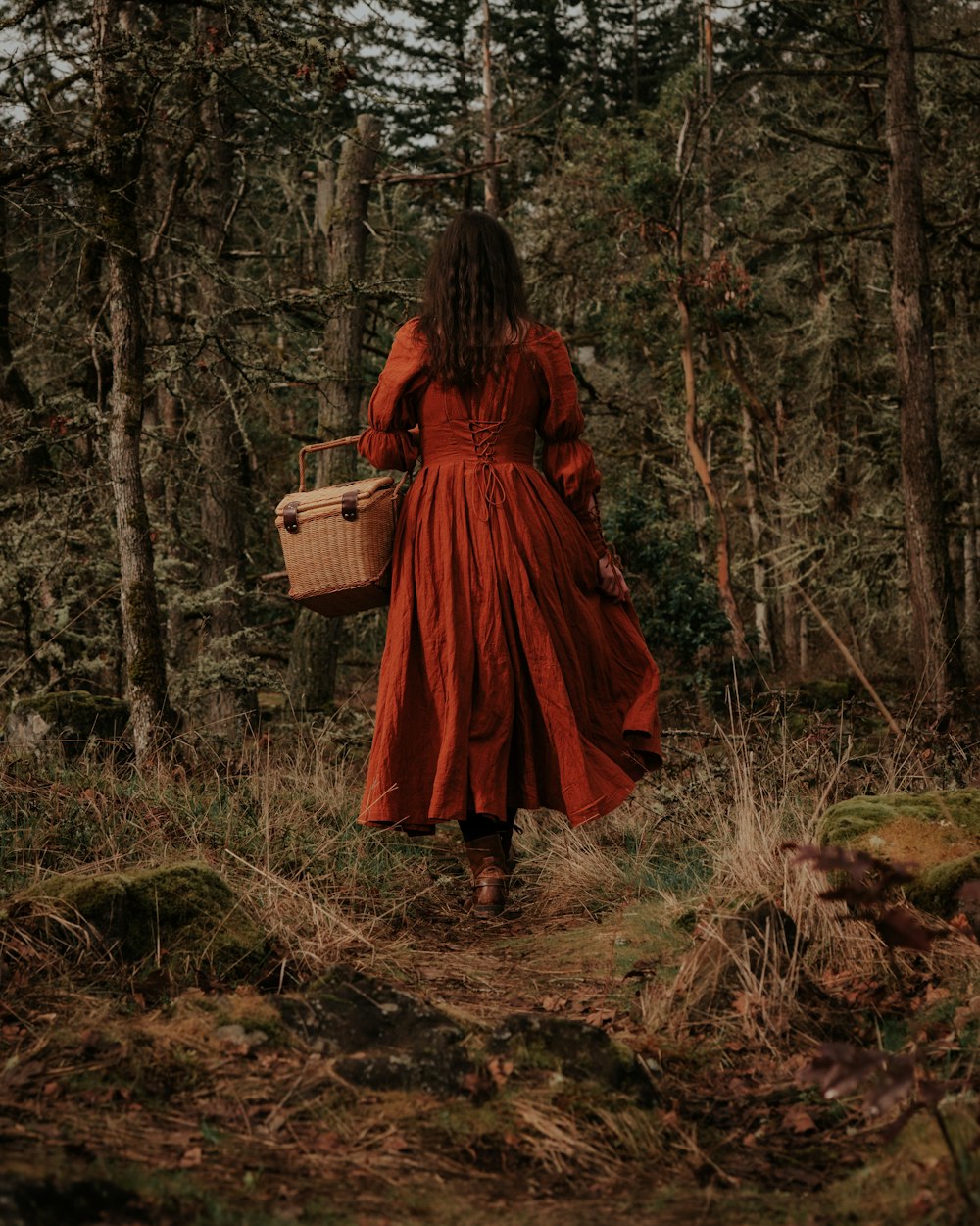 a woman in a red dress walking through a forest