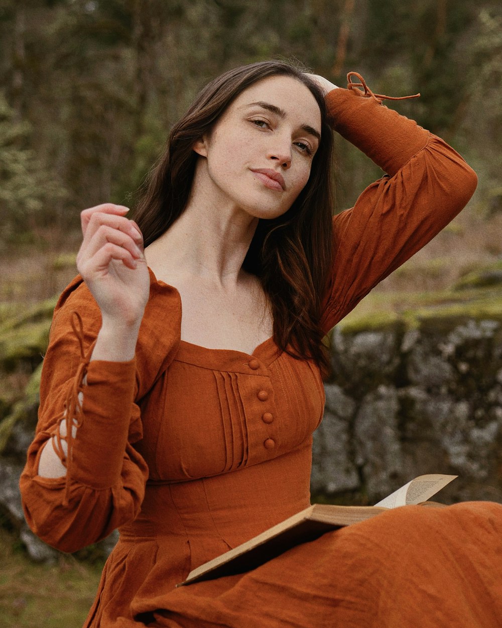 Una donna in un vestito arancione tiene in mano un libro