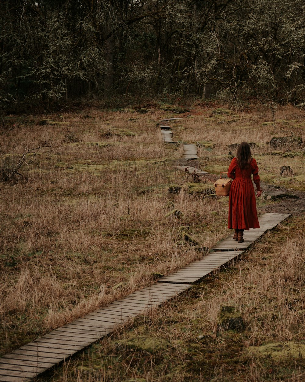 a woman in a red dress walking across a field