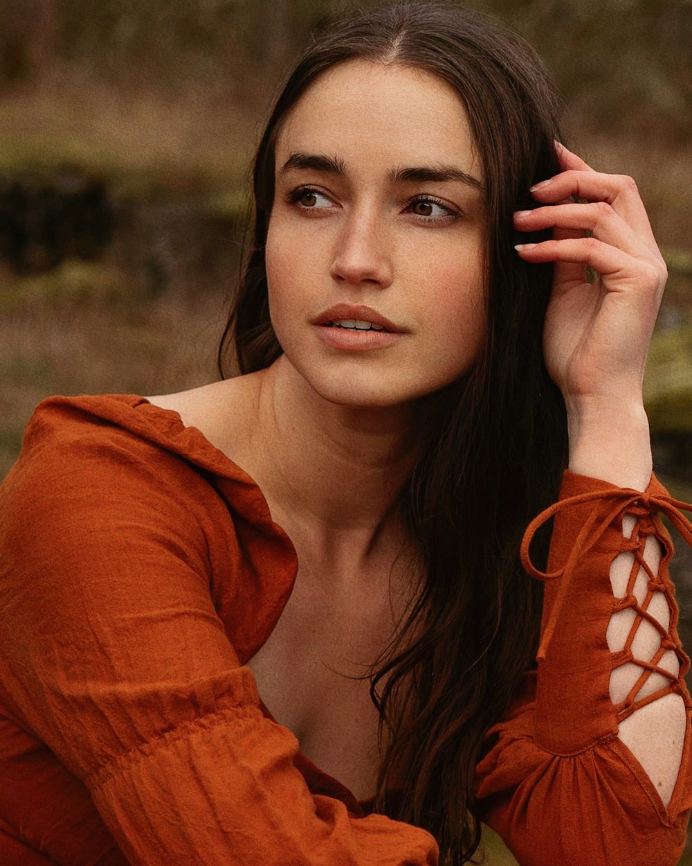 a woman with long hair wearing an orange shirt