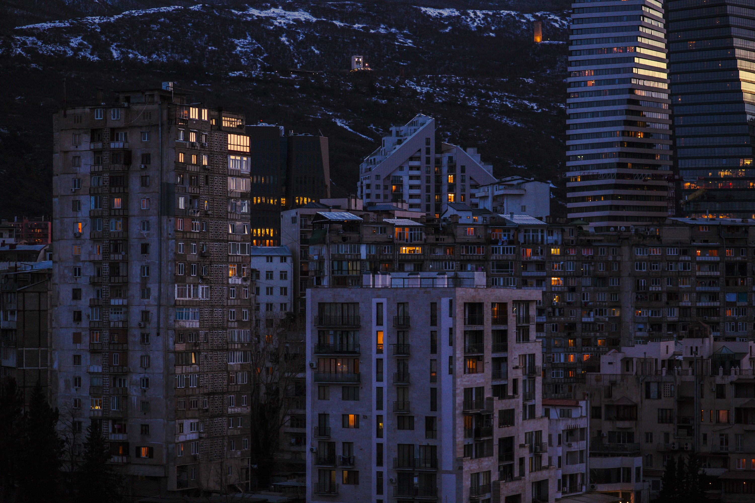 a view of a city at night with mountains in the background, 
