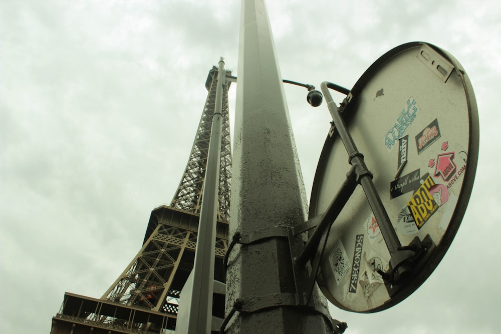 a street sign with stickers on it in front of the eiffel tower