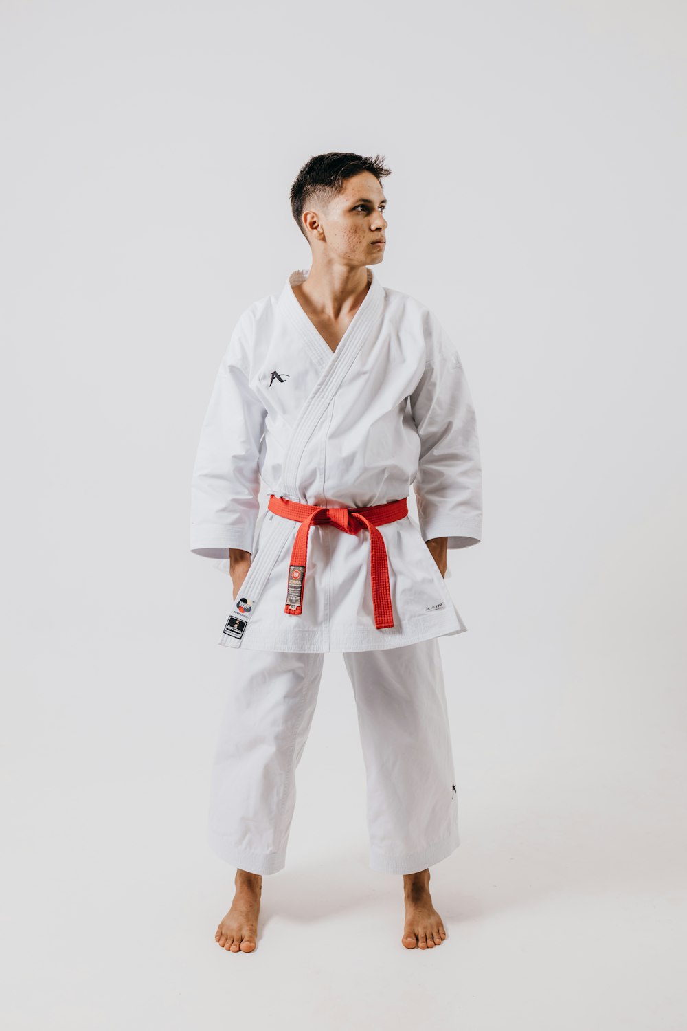 a man wearing a white karate suit and red belt