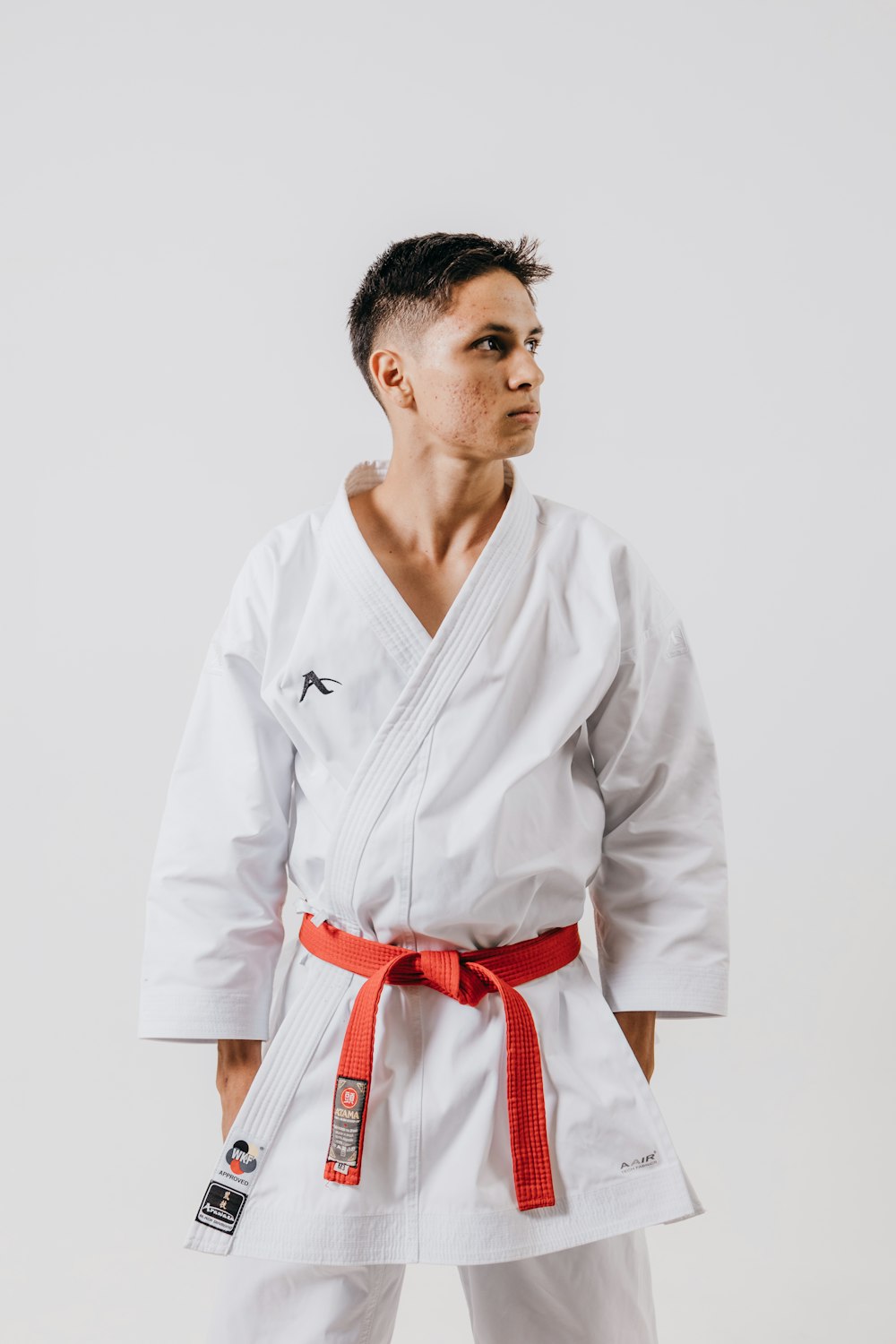 a man wearing a white karate suit and red belt