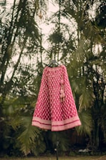 a pink and white dress on a stand in front of palm trees