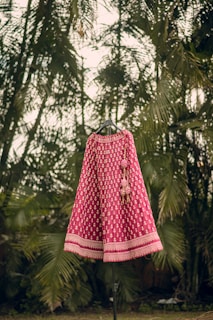 a pink and white dress on a stand in front of palm trees