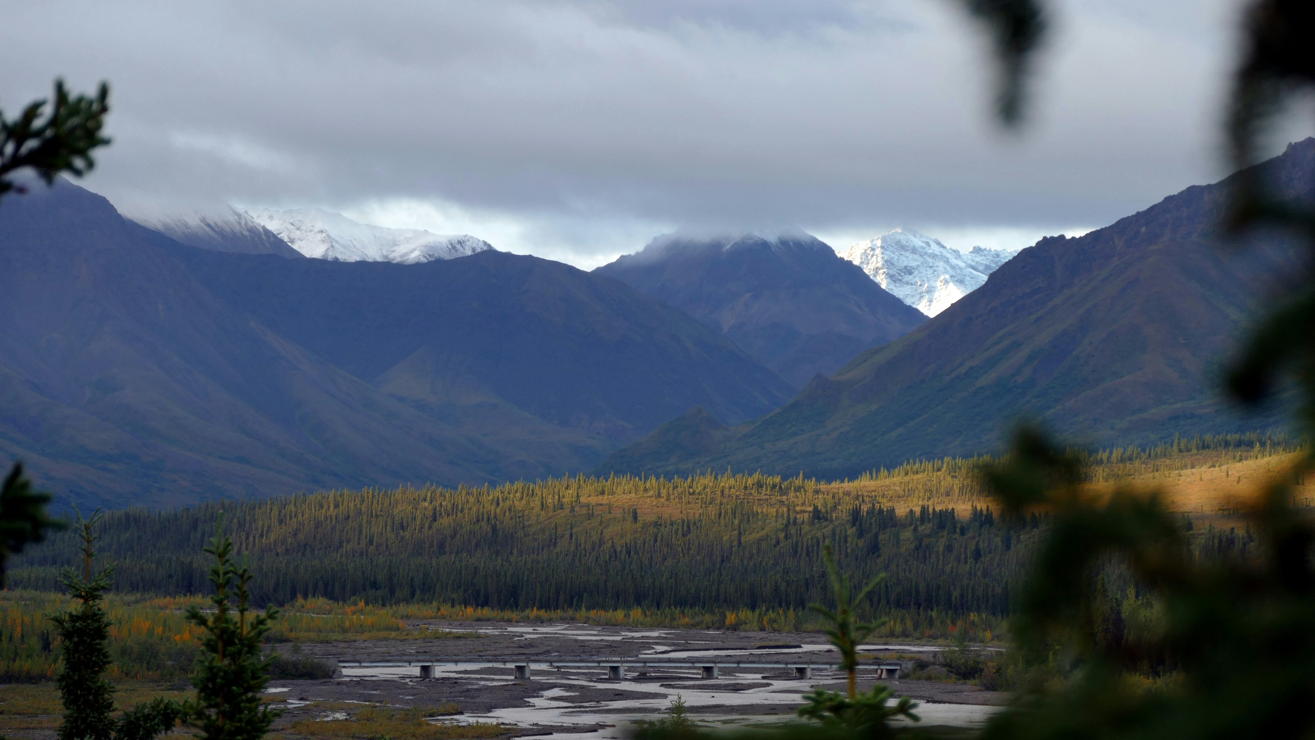 a view of a mountain range with a river in the foreground, Fall colors Denali National Park at runrise - Alaska