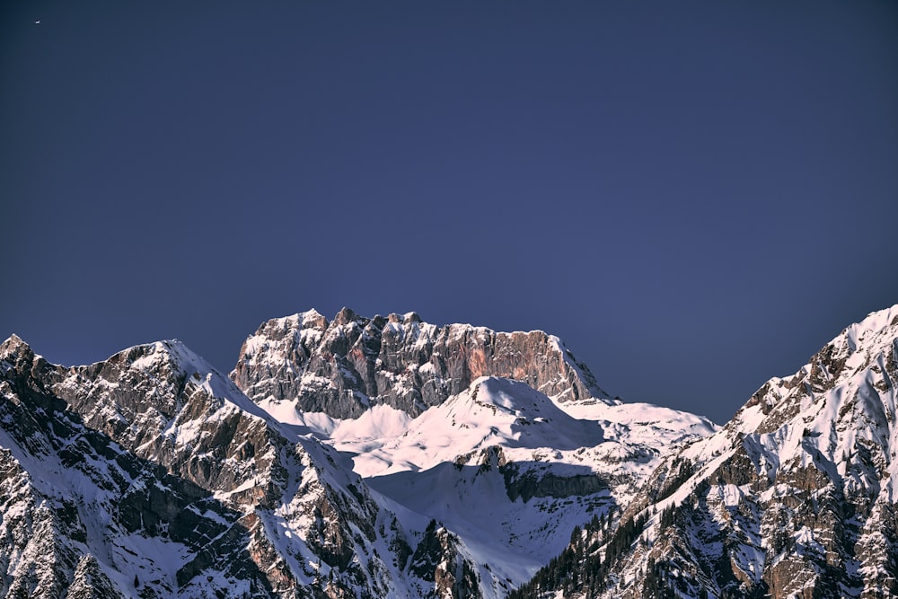 a snow covered mountain range with a moon in the sky