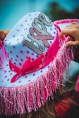 a woman wearing a pink and white hat with a name on it