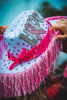 a woman wearing a pink and white hat with a name on it