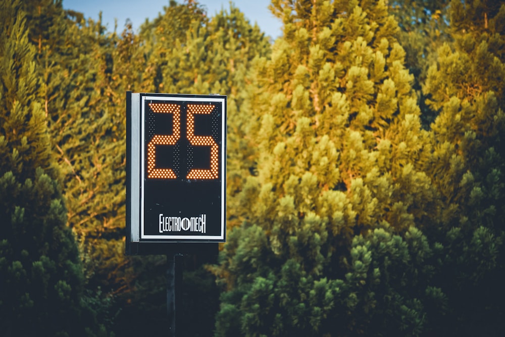 a digital clock is displayed in front of some trees