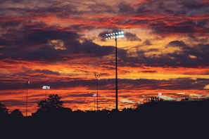 A sunset view over a packed stadium with fans silhouetted against the glowing sky.