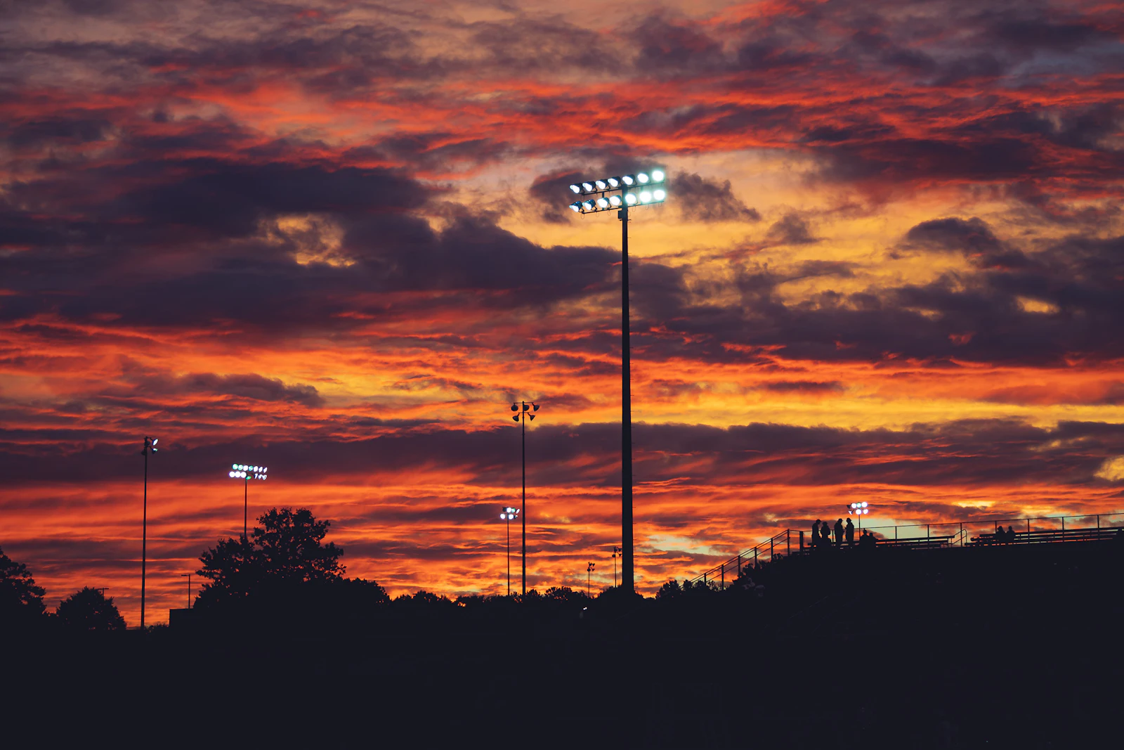 Stadium light tower silhouetted against a dramatic evening sky