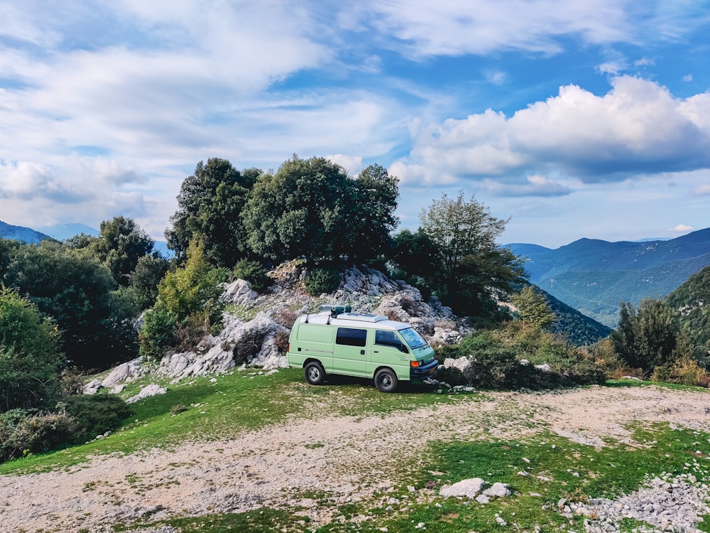 a van parked on top of a lush green hillside