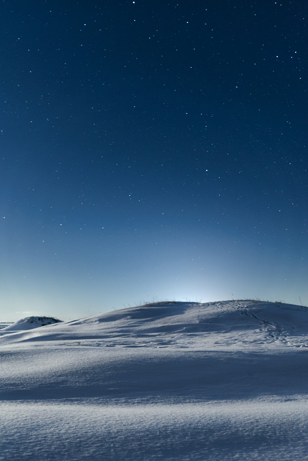 Una collina coperta di neve sotto un cielo blu con le stelle