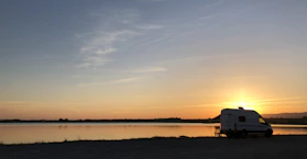 A sleek 2026 Weinsberg Carabus 600 DQ Grey Edition camper parked by a serene lake at sunset.