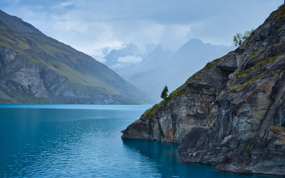 a body of water surrounded by mountains under a cloudy sky