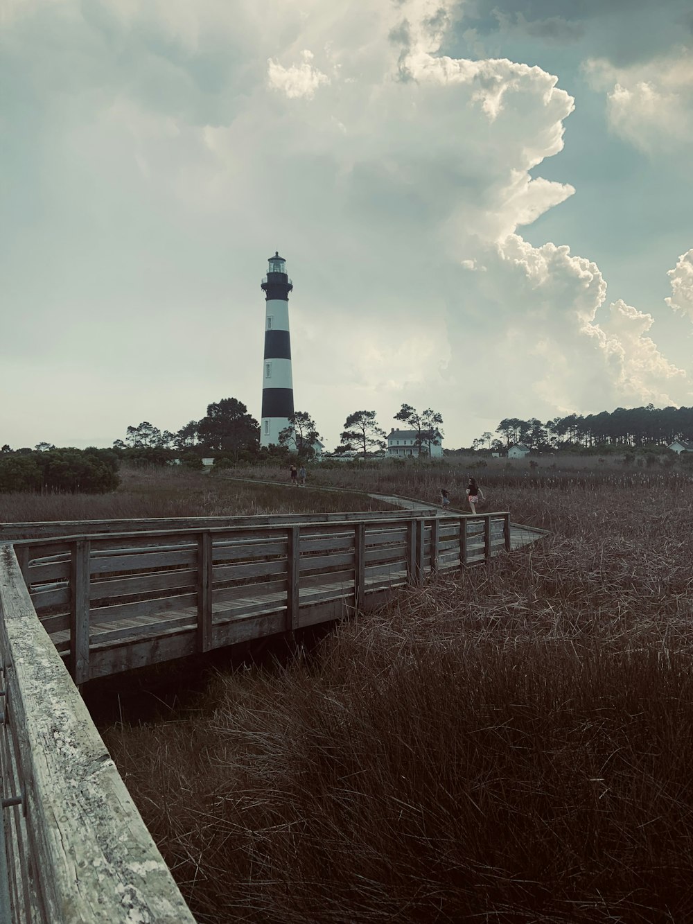 a person standing on a boardwalk next to a light house