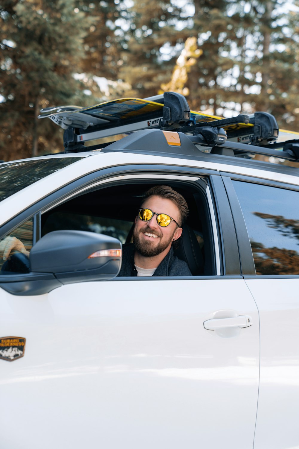 Ein Mann mit Sonnenbrille sitzt in einem weißen Auto