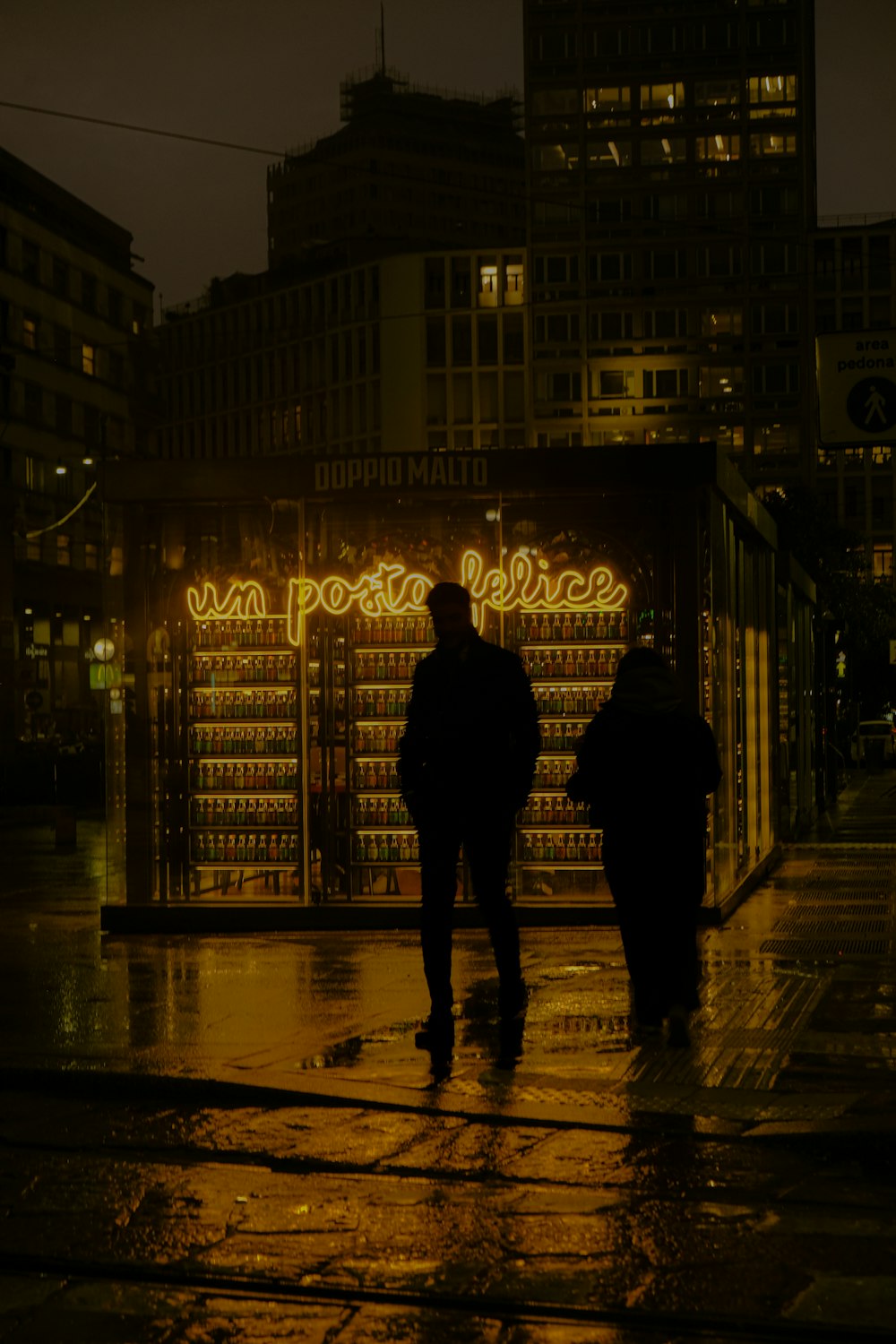 a couple of people walking down a street at night